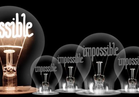 Large group of shining and dimmed light bulbs with fibers in a shape of Impossible and Possible words isolated on black background; concept of Motivation, Success and Change